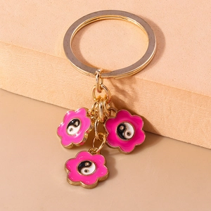 Vue détaillée du porte-clés doré avec fleurs roses et symboles Yin Yang Tai Chi