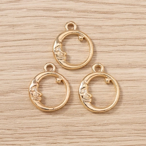 Macro view of gold crescent moon face charms with small star detail on wood background