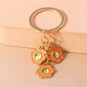 Détail d'un porte-clés doré avec fleurs en émail orange et motifs Yin Yang Tai Chi