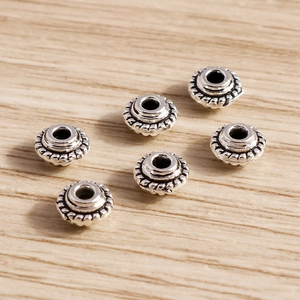 Vista macro de cuentas espaciadoras de plata vintage para bisutería DIY en madera