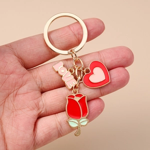 Détail d'un porte-clés en or rose avec plaque LOVE, fleur de rose et breloques cœur