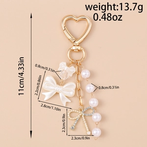 Detailed view of light gold heart keychain with resin bow and pearl charms for women