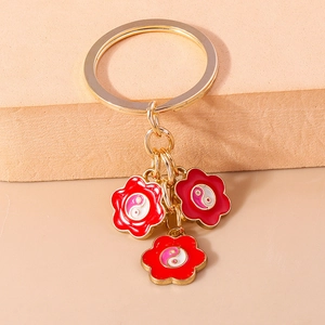 Détail d'un porte-clés doré avec pendentifs floraux et symboles Yin Yang roses et blancs