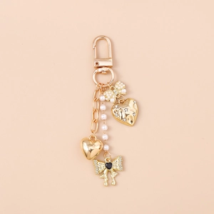 Close-up of golden bow keychain with pearl heart charms and decorative d-ring clasp