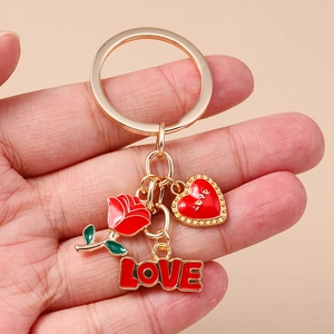 Détails macro d'une rose en émail rouge et de breloques cœur LOVE sur un porte-clés doré