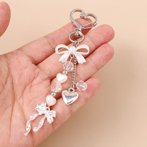 Detail of sweet heart pearl keychain with white resin bow and silver carabiner clip
