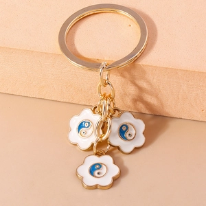 Détail du porte-clés doré en forme de cœur avec motif Yin Yang Tai Chi sur fond pêche
