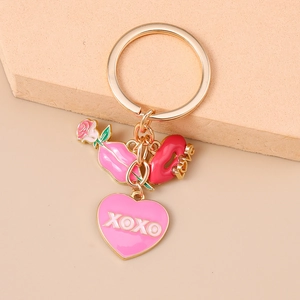 Détail du porte-clés doré avec cœur rose XOXO, lèvres rouges LOVE et pendentif rose