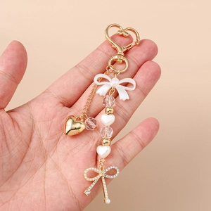 Fashionable heart keychain with white bow, pearls and crystals in gold finish