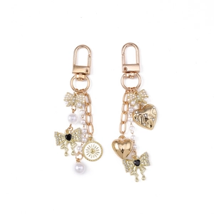 Set of 2 golden bow and pearl keychains with heart charms and sunburst tags