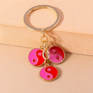 Détail de breloques Yin Yang en forme de cœur émaillé doré sur un porte-clés créatif
