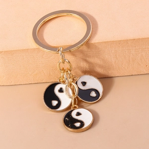 Détail d'un porte-clés Tai Chi doré avec motif yin yang en cœur et anneaux métalliques