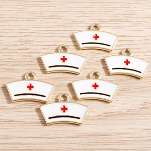 Nurse cap enamel charms with red cross and gold trim on light wood background