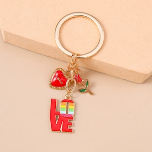 Détail d'un porte-clés doré avec cœur rouge, rose et pendentif LOVE arc-en-ciel