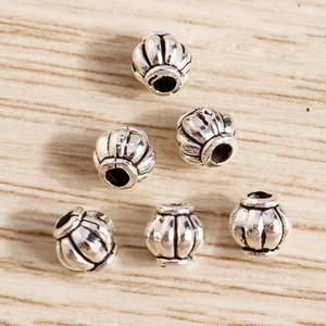 Detalle de seis cuentas de calabaza plateadas con acabado vintage para joyería artesanal