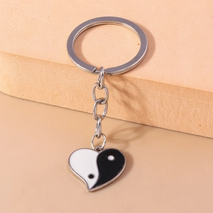 Détail d'un porte-clés cœur yin yang avec finition en émail noir et blanc