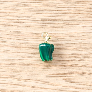 Macro shot of green chili pepper pendant with gold ring and detailed oil drip finish