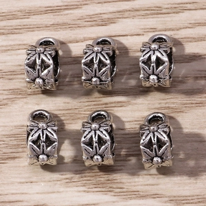 Retro silver floral spacer beads with 6-petal flower relief on a vintage wood background