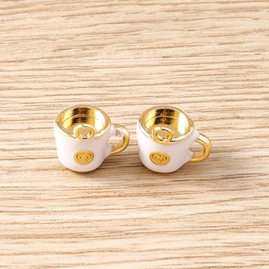 Detail of teapot cup charms in gold finish with white enamel heart relief pattern