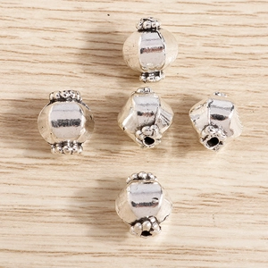 Vista macro de cuentas espaciadoras de plata vintage con motivos florales para joyería DIY