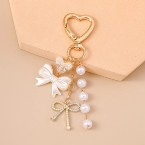 Detail view of pearl bow keychain with heart clasp on elegant display pedestal