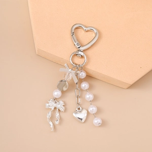 Detail of silver heart keychain with elegant white pearls and a delicate bow charm