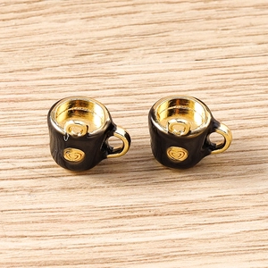 Detail of mini teapot pendants with gold heart relief and black enamel for DIY jewelry