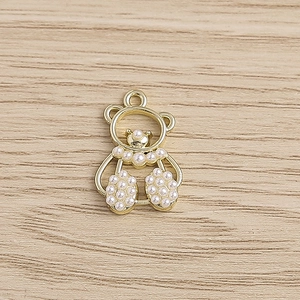 Detail of bear pendant with gold hollow frame and white faux pearls on wood background