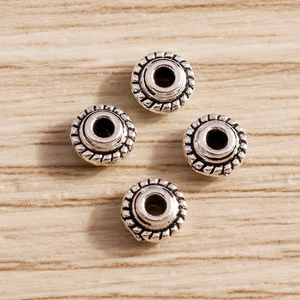 Detalle de cuatro cuentas de plata vintage con textura de cuerda para joyería DIY