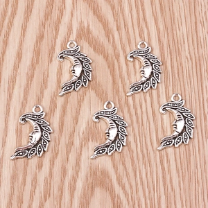 Macro detail of five antique silver crescent moon face alloy charms on wooden background