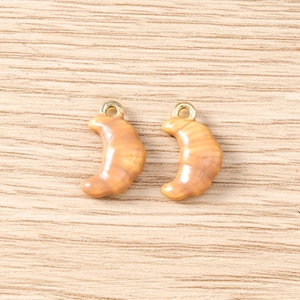Detailed macro view of croissant-shaped resin charms with gold metal rings for DIY jewelry