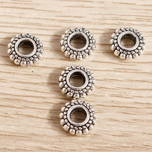 Detalle macro de cinco cuentas espaciadoras de girasol en plata antigua para joyas