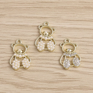 Detailed macro view of three cute teddy bear charms with pearls and rhinestones on wood