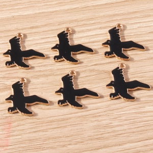 Detailed view of bird-shaped enamel charms in black and gold for DIY jewelry making
