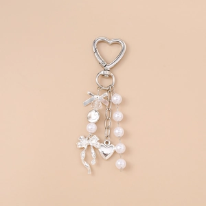 Close-up of heart carabiner with silver bow, white pearls, and heart charm detail