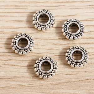 Detalle macro de cinco cuentas espaciadoras de aleación de plata vintage sobre madera