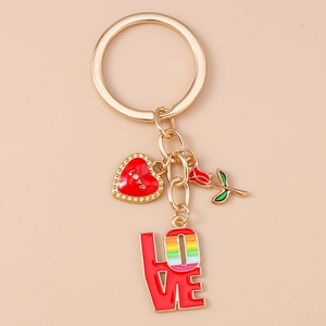 Détail d'un porte-clés LOVE doré avec rose émaillée et breloques cœur sur fond rose