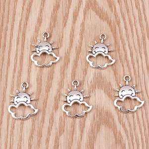 Detail view of five vintage silver sun and cloud charms on a wooden background