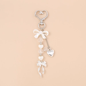 Detail view of heart keychain featuring white pearls and a stylish ribbon bow ornament