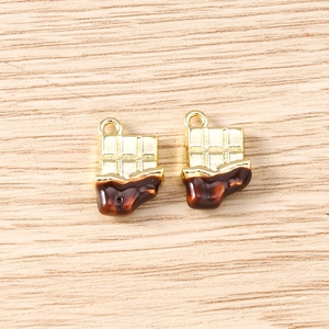 Detailed view of two gold and brown chocolate bar pendants with small rings on wood