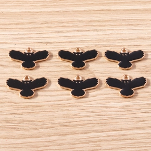 Detailed macro view of 6 black and gold owl charms for DIY jewelry making on wood