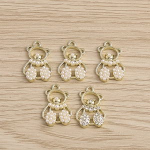 Detailed close-up of golden bear-shaped jewelry charms with white pearls and rhinestones