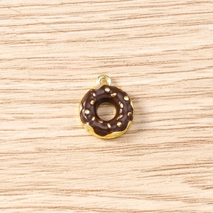 Macro view of a chocolate donut pendant charm with gold accents and cream sprinkles