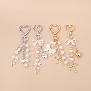 Detailed view of fashion heart keychains with pearls and bows in gold and silver finish