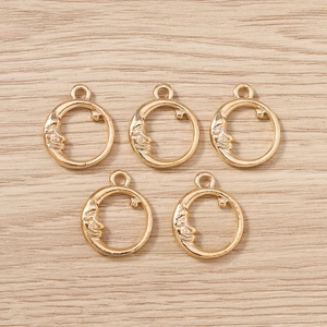 Detail of five golden celestial moon and star charms on a light wood background