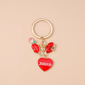 Détail du porte-clés doré avec cœur XOXO, lèvres Love et pendentif fleur de rose