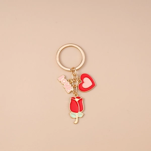 Détail du porte-clés doré avec lettres LOVE roses, rose rouge et pendentifs en forme de cœur