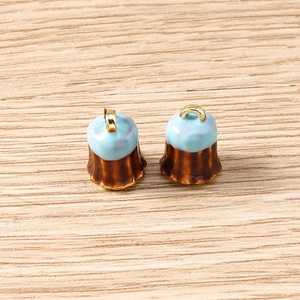 Detailed view of two blue and brown canelé pendant charms with gold metal loops