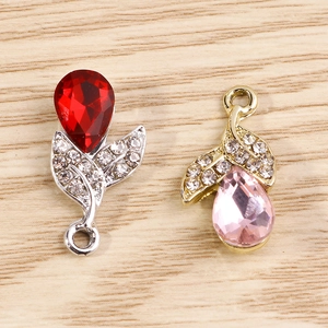 Detailed macro view of silver and gold flower charms with red and pink crystal teardrops