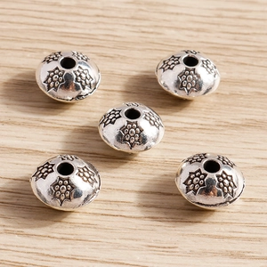 Detalle macro de cinco cuentas espaciadoras de aleación de plata retro para joyería DIY